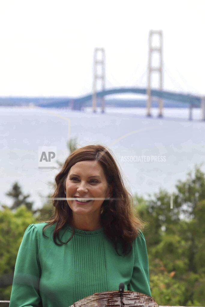 In this June 10, 2021 photo provided by the Michigan Office of the Governor, Gov. Gretchen Whitmer speaks at Straits State Park in St. Ignace, Mich., with the Mackinac Bridge behind her. Whitmer called for spending a "historic" $250 million in federal coronavirus relief aid to upgrade state parks and trails, a day after Senate Republicans announced a $1.5 billion plan to fix deteriorating local bridges across Michigan. (Michigan Office of the Governor via AP)