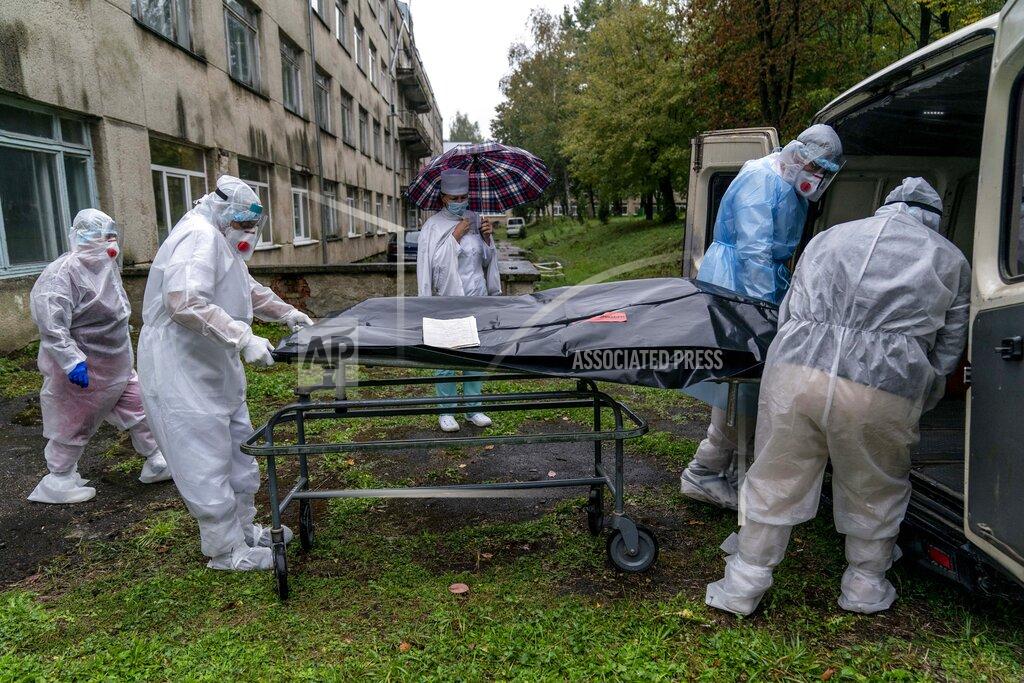 Evgeniy Maloletka Medical workers move the body of a patient who died from the coronavirus at a hospital in Stebnyk, Ukraine, on Wednesday, Sept. 30, 2020. As coronavirus cases increase, every bed in the hospital in this city in western Ukraine is in use and its chief doctor is watching the surge with alarm and anguish. (AP Photo/Evgeniy Maloletka)