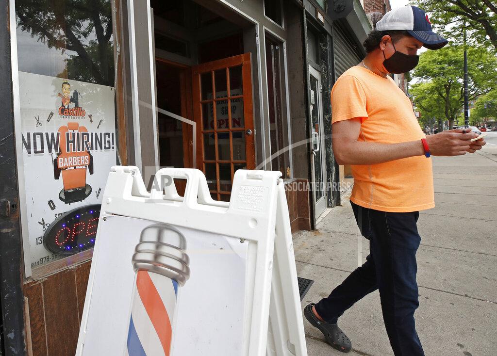 Elise Amendola Barber Luis Garcia walks out of the Castillo Barbershop where a sign "Now Hiring" is displayed, Friday, June 5, 2020, in Lawrence, Mass. The U.S. unemployment rate fell to 13.3% in May, and 2.5 million jobs were added — a surprisingly positive reading in the midst of a recession that has paralyzed the economy and depressed the job market in the wake of the viral pandemic. (AP Photo/Elise Amendola)