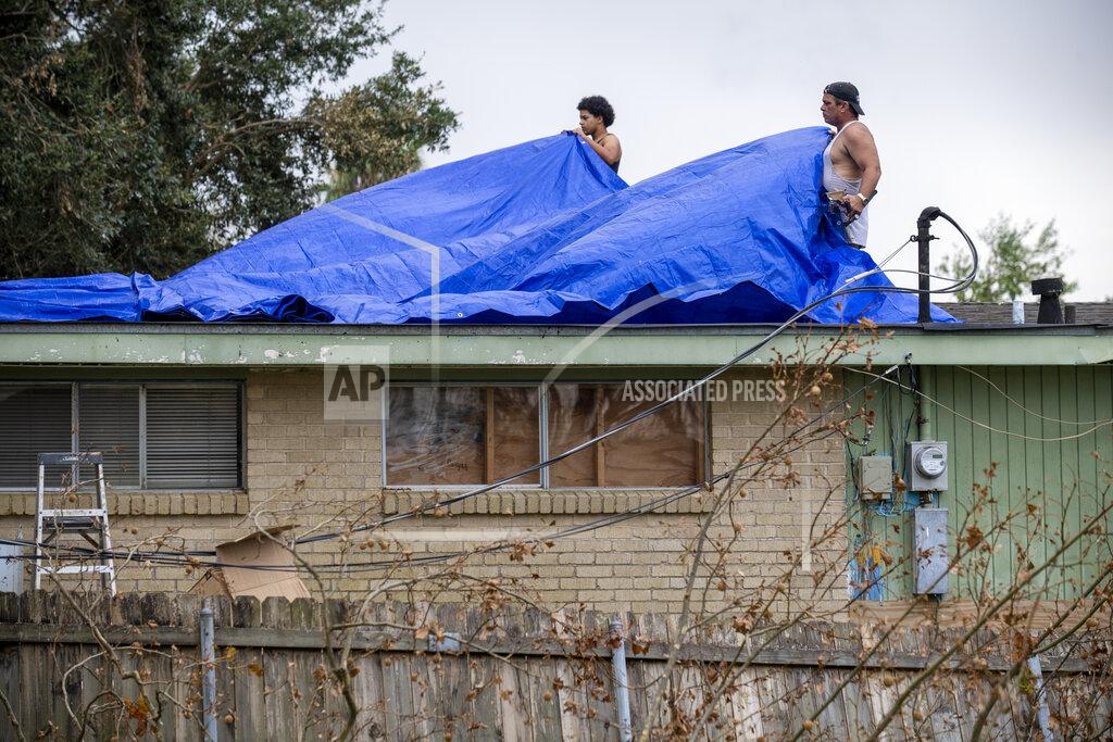 Chris Granger Men cover a roof with tarps, Monday, Sept. 6, 2021, a week after Hurricane Ida swept through the area. (Chris Granger/The Times-Picayune/The New Orleans Advocate via AP)