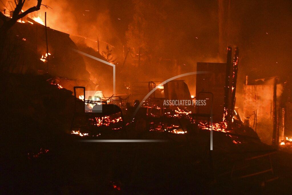 Michael Svarnias Fire burns makeshift tents outside the perimeter of the overcrowded refugee camp at the port of Vathy on the eastern Aegean island of Samos, Greece, late Sunday, Sept. 19, 2021. A fire has broken out at a soon-to-be-closed migrant camp on the Greek island of Samos, forcing its evacuation. The transfer of the migrants to the new, €43 million ($50 million) facility was due to begin Monday and be completed by Wednesday. (AP Photo/Michael Svarnias)