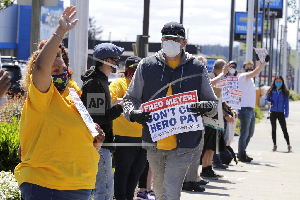 Ted S. Warren Members and supporters of the United Food and Commercial Workers International Union take part in a protest outside the Fred Meyer grocery store in Burien, Wash., against Fred Meyer's parent company Kroger, Friday, May 15, 2020. Kroger officials have said they are ending the additional $2 hourly "hero pay" bonus that had been paid to workers since late March during the coronavirus pandemic. The company said Friday it will now offer one-time bonus payments of $400 and $200 for full- and part-time employees to be paid in two installments. (AP Photo/Ted S. Warren)