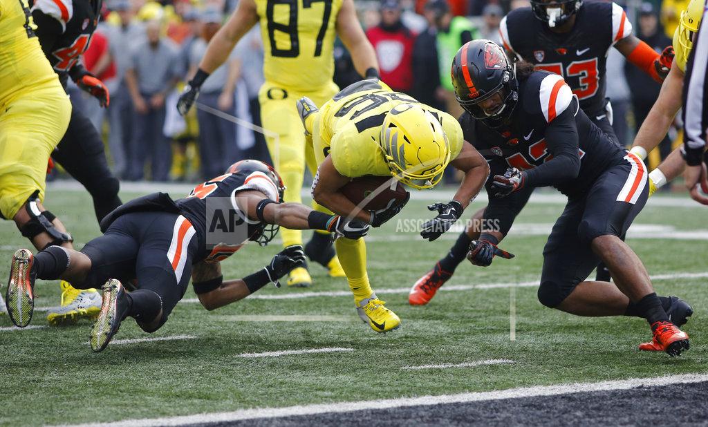 Timothy J. Gonzalez Oregon running back Travis Dye, center, tries to get past Oregon State's Jeffrey Manning Jr., left, and Doug Taumoelau, right, in the first half of an NCAA football game in Corvallis, Ore., on Friday, Nov. 23, 2018. (AP Photo/Timothy J. Gonzalez)