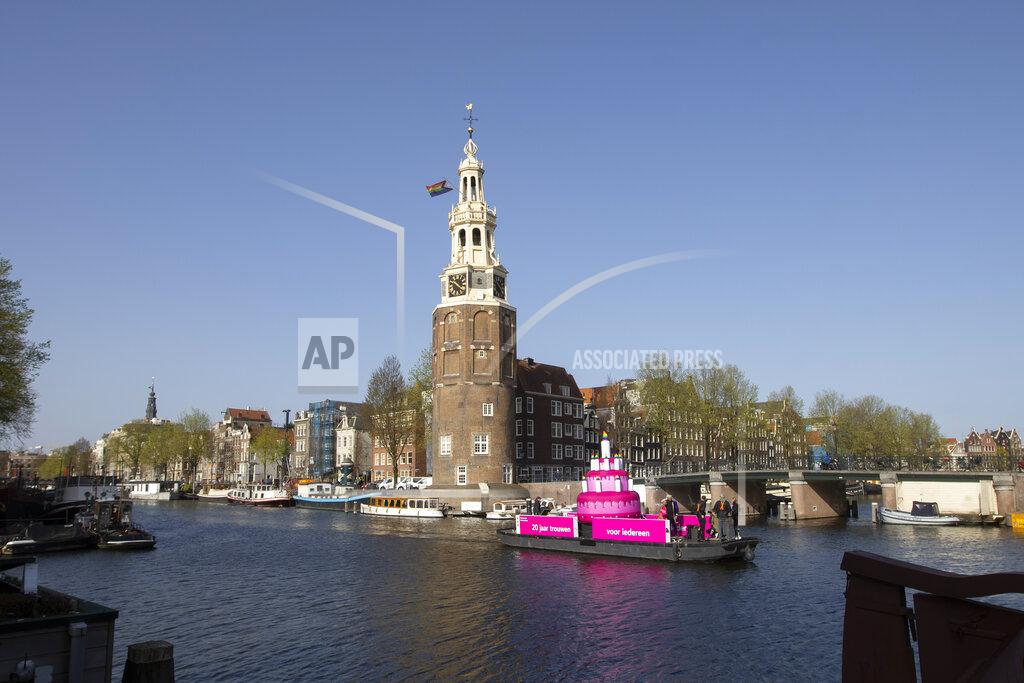 Peter Dejong A huge inflatable pink cake with candles spouting rainbow flames glided through the Amsterdam canals Thursday as the Dutch capital celebrated the 20th anniversary of the world's first legal same-sex marriages, Thursday, April 1, 2021. Twenty years ago, the mayor of Amsterdam married four couples in City Hall as the Netherlands became the first country in the world with legalized same-sex marriage. It's now legal in 28 countries. (AP Photo/Peter Dejong)