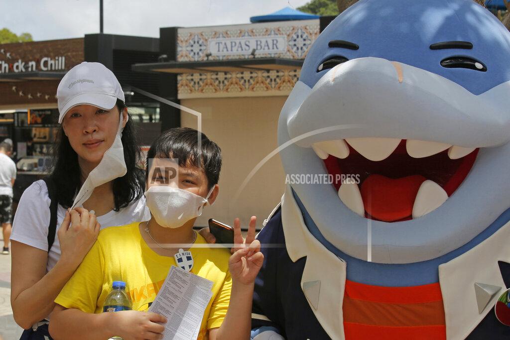 Kin Cheung A woman takes off her face mask for a photograph at the Ocean Park amusement park in Hong Kong, Saturday, June 13, 2020. Hong Kong's Ocean Park reopened Saturday after nearly four months of closure due to the coronavirus pandemic. The animal and nature-themed attraction combines pandas, penguins, roller coasters and other rides, and has been a Hong Kong icon since its opening in 1977. (AP Photo/Kin Cheung)