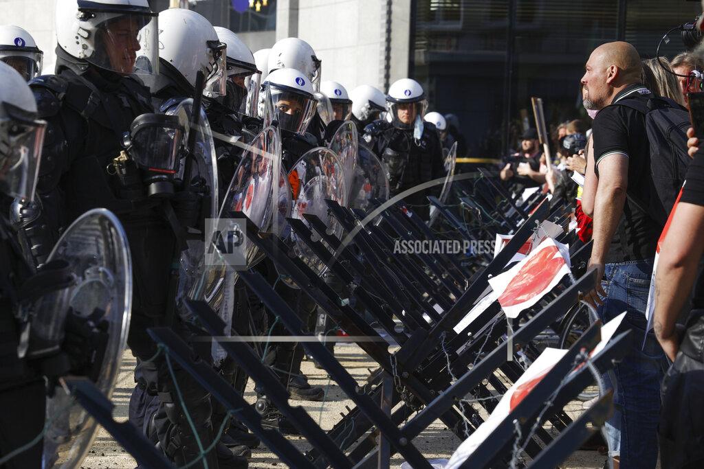 Olivier Matthys Police officers, in full anti-riot gear, set a security line as people gather near EU headquarters during a so called "European Demonstration for Freedom and Democracy" protest against COVID-19 security measures taken by European governments, in Brussels, Saturday, May 29, 2021. (AP Photo/Olivier Matthys)