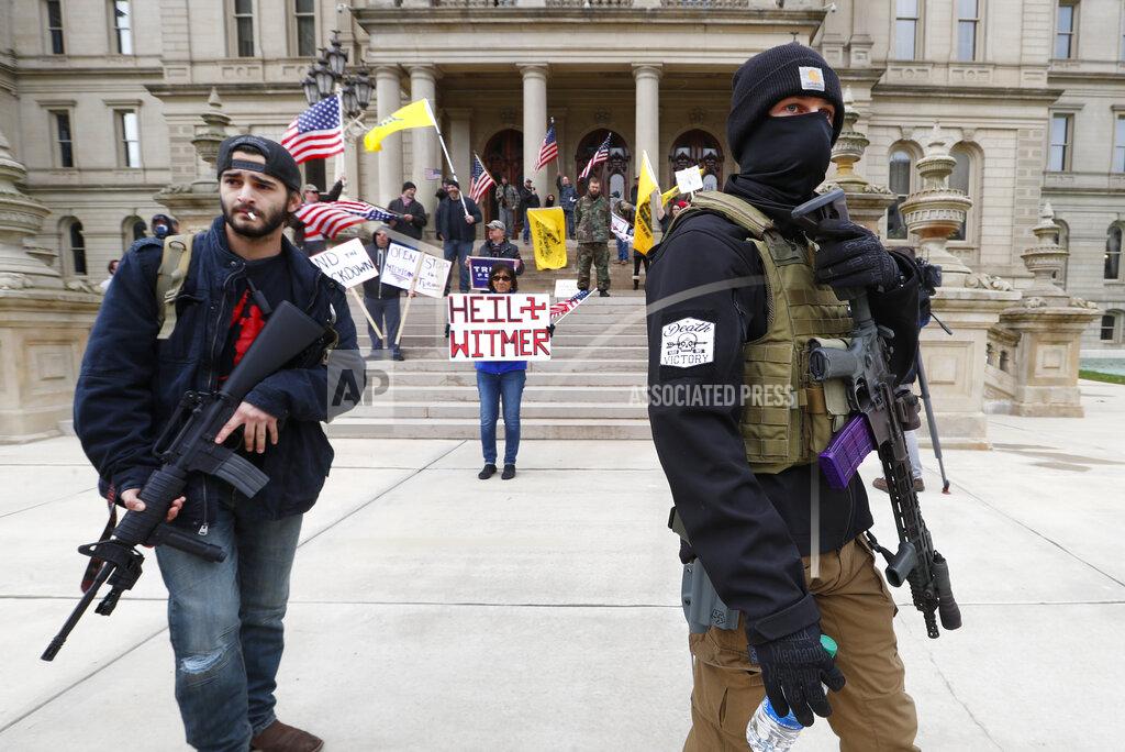 Paul Sancya Protesters carry rifles near the steps of the Michigan State Capitol building in Lansing, Mich., Wednesday, April 15, 2020. Flag-waving, honking protesters drove past the Michigan Capitol on Wednesday to show their displeasure with Gov. Gretchen Whitmer's orders to keep people at home and businesses locked during the new coronavirus COVID-19 outbreak. (AP Photo/Paul Sancya)