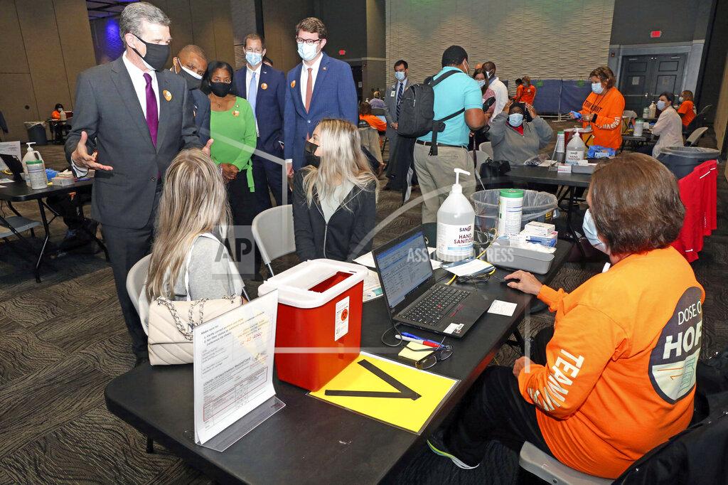 Deborah Griffin North Carolina Gov. Roy Cooper greets two East Carolina University students receiving their COVID-19 vaccination during the governor's tour of the Vidant Health/Pitt County large-scale vaccine clinic at the Greenville Convention Center in Greenville, N.C., Friday, March 19, 2021. (Deborah Griffin/The Daily Reflector via AP)