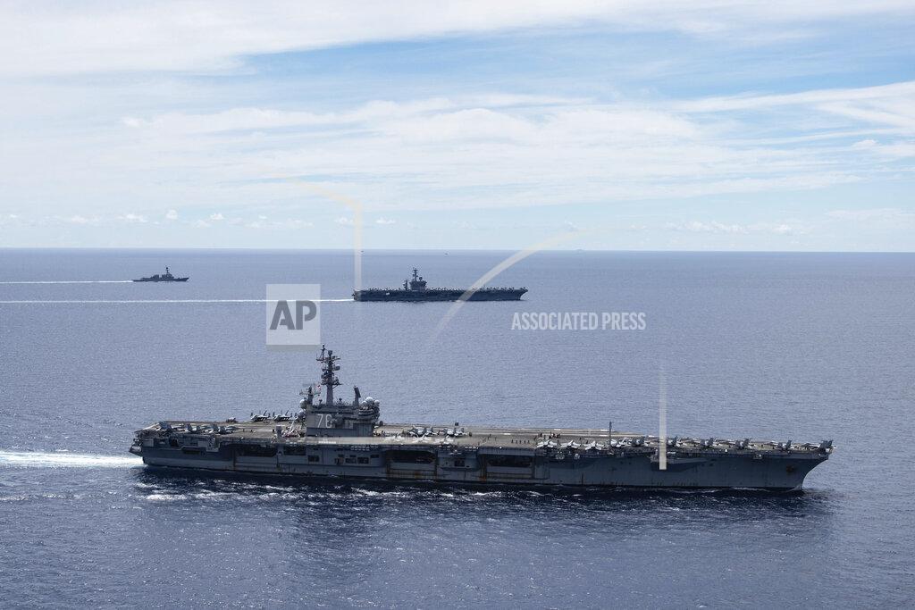 In this photo provided by U.S. Navy, the USS Ronald Reagan (CVN 76, front) and USS Nimitz (CVN 68, rear) Carrier Strike Groups sail together in formation, in the South China Sea, Monday, July 6, 2020. China on Monday, July 6, accused the U.S. of flexing its military muscles in the South China Sea by conducting joint exercises with two U.S. aircraft carrier groups in the strategic waterway.(Mass Communication Specialist 3rd Class Jason Tarleton/U.S. Navy via AP)