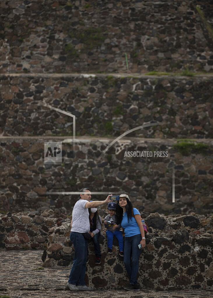 Tourists take selfies in front of the Pyramid of the Sun in Teotihuacan, Mexico, early Thursday, Sept. 10, 2020. After closing for five months due to the restrictions imposed by the COVID-19 pandemic, “The city of the gods” opens its doors to visitors once again on Thursday, but at a reduced capacity of 30%. (AP Photo/Fernando Llano)