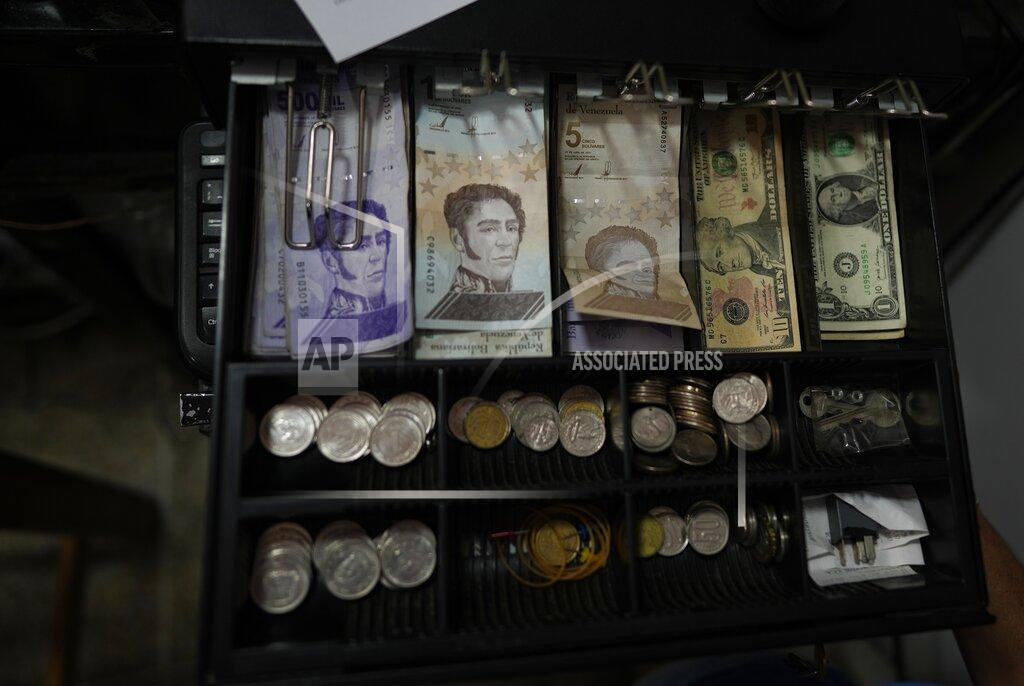 Ariana Cubillos A cash register drawer holds Bolivars and U.S. currencies at a shop in Caracas, Venezuela, Friday, May 13, 2022. A new tax law approved by the Venezuelan government, that went into effect in March, applies a 3% tax charge on transactions paid in foreign currencies. (AP Photo/Ariana Cubillos)
