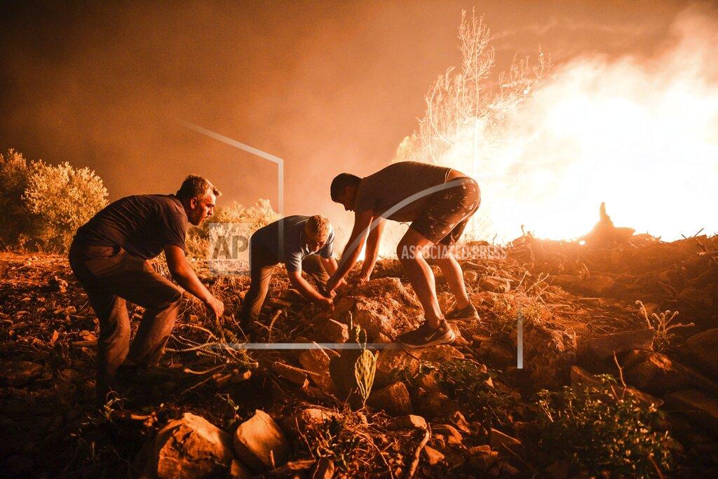 Uncredited Local villagers try to get the fire under control in Kirli village near the town of Manavgat, in Antalya province, Turkey, early Friday July 30, 2021. The fire that continued all night could not be brought under control and people living in the village started to evacuate. Wildfires are common in Turkey's Mediterranean and Aegean regions during the arid summer months, although some previous forest fires have been blamed on arson. (AP Photo)