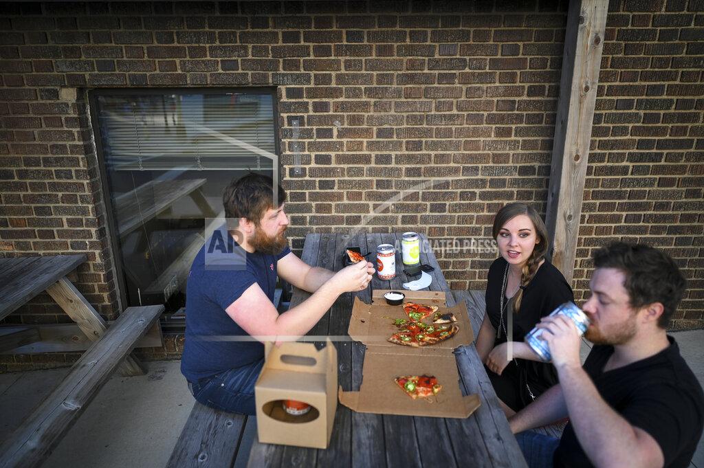 Aaron Lavinsky From left, Steven, no last name given, Tiffanie Winders and Verdon Kleimenhagen drink beer and eat pizza outside Black Sheep in the North Loop, Wednesday, May 20, 2020, in Minneapolis, amid the coronavirus pandemic. (Aaron Lavinsky/Star Tribune via AP)