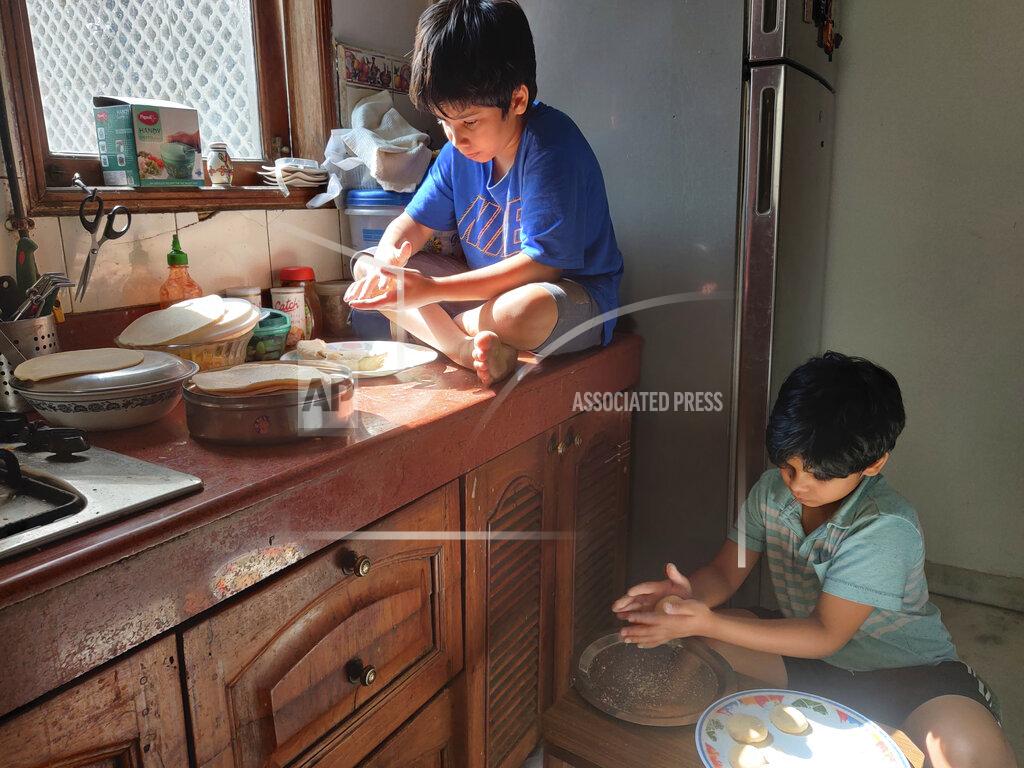 Anil Sanweris In this Sunday, April 19, 2020 photo provided by Anil Sanweria, his sons, Uddhav Pratap, 8, left, and Advait Vallabh, 9, help in the kitchen during a nationwide COVID-19 coronavirus lockdown. The brothers believe the lockdown should continue for a year. “They shouldn’t reopen till the time there are zero cases left,” the younger Uddhav Pratap says. (Anil Sanweria via AP)