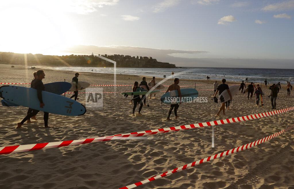 Rick Rycroft Surfers prepare to enter the water at Bondi Beach in Sydney, Tuesday, April 28, 2020, as coronavirus pandemic restrictions are eased. The beach is open to swimmers and surfers to exercise only. (AP Photo/Rick Rycroft)
