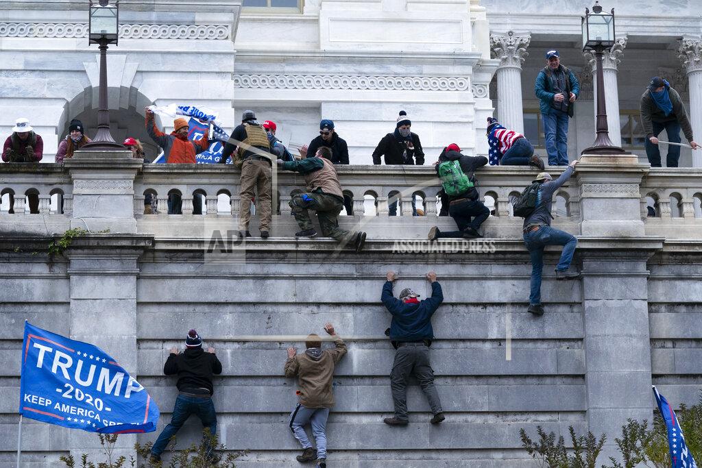 Supporters of President Donald Trump climb the West wall of the the U.S. Capitol on Wednesday, Jan. 6, 2021, in Washington. (AP Photo/Jose Luis Magana)