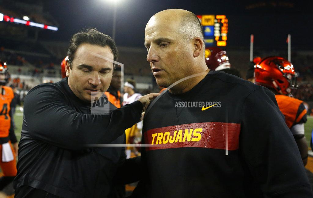 Timothy J. Gonzalez Oregon State head coach Jonathan Smith, left, meets Southern California head coach Clay Helton after the Trojans' 38-21 victory in an NCAA college football game in Corvallis, Ore., on Saturday, Nov. 3, 2018. (AP Photo/Timothy J. Gonzalez)