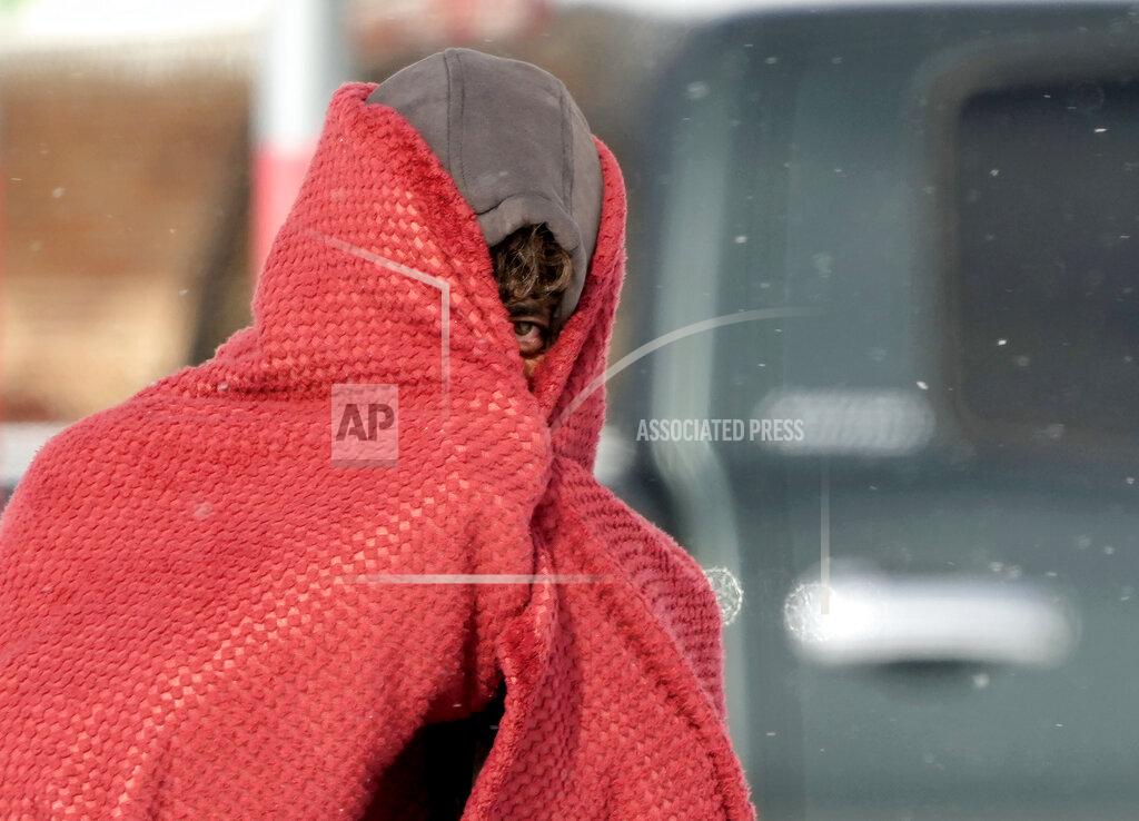 David J. Phillip A man peers out from under a blanket while trying to stay warm in below freezing temperatures Monday, Feb. 15, 2021, in Houston. A winter storm dropping snow and ice sent temperatures plunging across the southern Plains, prompting a power emergency in Texas a day after conditions canceled flights and impacted traffic across large swaths of the U.S. (AP Photo/David J. Phillip)