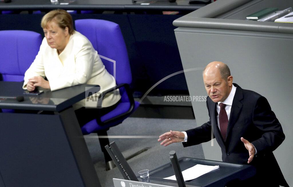 Michael Sohn FILE - In this Sept. 29, 2020 file photo, German Finance Minister Olaf Scholz, right, delivers a speech beside German Chancellor Angela Merkel, left, during a budget debate as part of a meeting of the German federal parliament, Bundestag, at the Reichstag building in Berlin, Germany, Tuesday, Sept. 29, 2020. The coronavirus pandemic is colliding with politics as Germany embarks on its vaccination drive and one of the most unpredictable election years in its post-World War II history. (AP Photo/Michael Sohn, File)