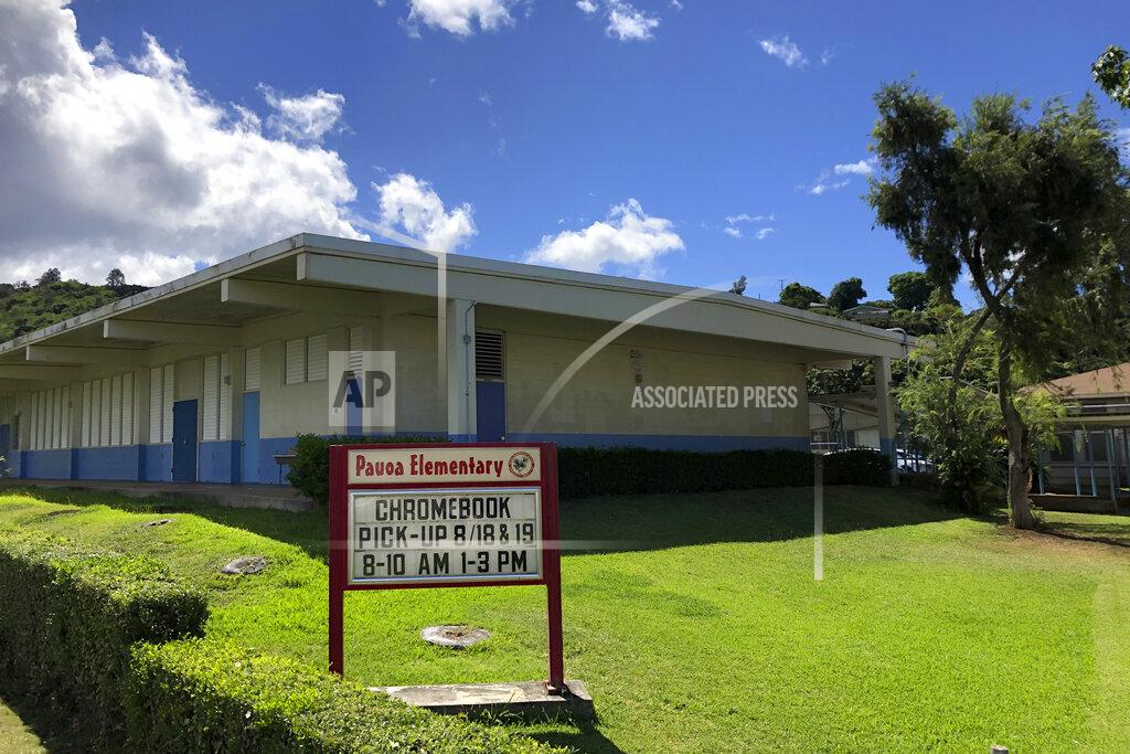 Jennifer Sinco Kelleher A sign at Pauoa Elementary School in Honolulu on Monday, August 17, 2020, informs students when to pick-up computers for distance learning. Many Hawaii public school students are spending the first day of school online as coronavirus cases surge, mostly on the island of Oahu, where Honolulu is located. (AP Photo/Jennifer Sinco Kelleher)