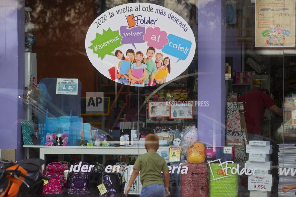 Paul White A boy plays in front of a store selling children's school stationery, backpacks, protective masks and hand sanitizers in Madrid, Spain, Monday, Aug. 24, 2020. Poster in Spanish reads '2020, the return to school most wished for. We want to go back to school'. Despite a spike in coronavirus infections, authorities in Europe are determined to send children back to school. Schools in the Spanish capital are scheduled to open on Sept. 4. (AP Photo/Paul White)