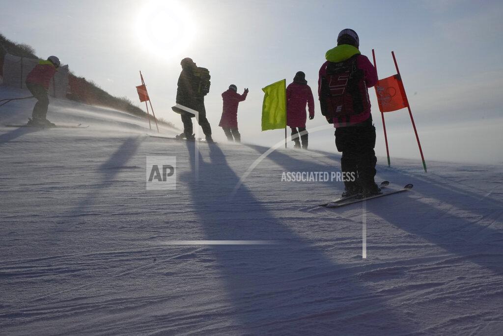 Robert F. Bukaty Officials stand on the course as a gust of wind blows powder across the slopes of the course for the women's combined downhill at the 2022 Winter Olympics, Thursday, Feb. 17, 2022, in the Yanqing district of Beijing. (AP Photo/Robert F. Bukaty)