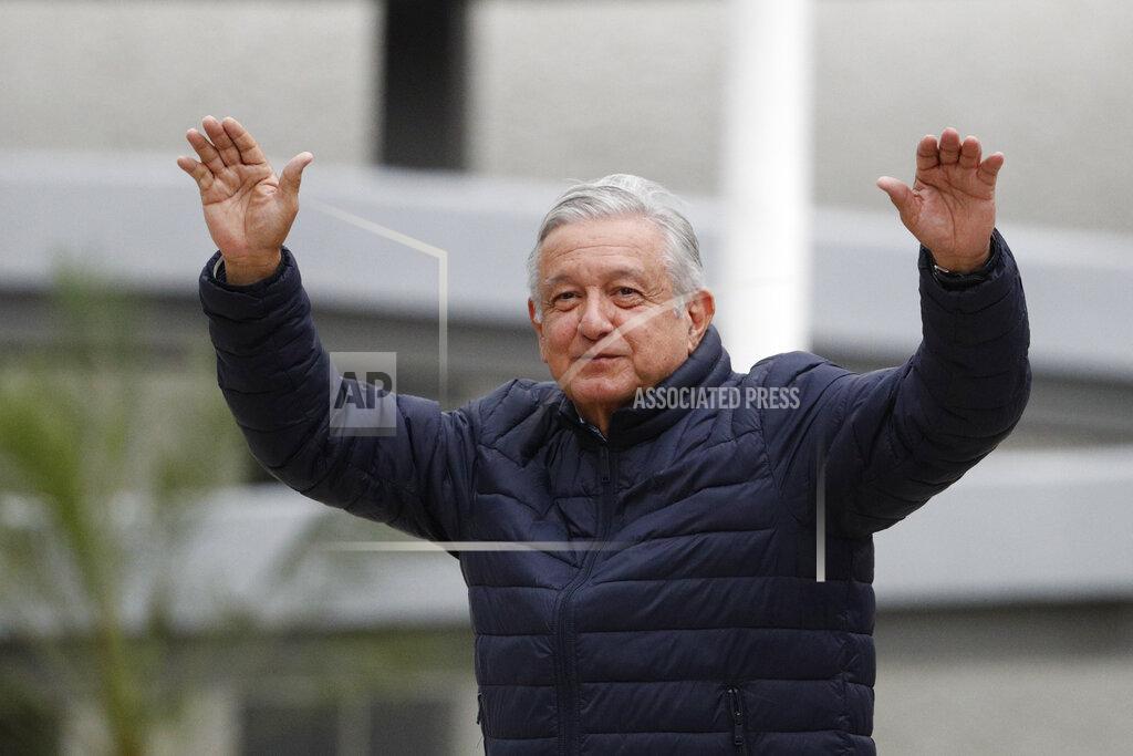 FILE - In this April 3, 2020 file photo, Mexican President Andres Manuel Lopez Obrador waves to supporters cheering from over an outside wall, after visiting a Mexican Social Security Institute (IMSS) hospital that will be converted to receive COVID-19 patients in the Coyoacan district of Mexico City. (AP Photo/Rebecca Blackwell, File)