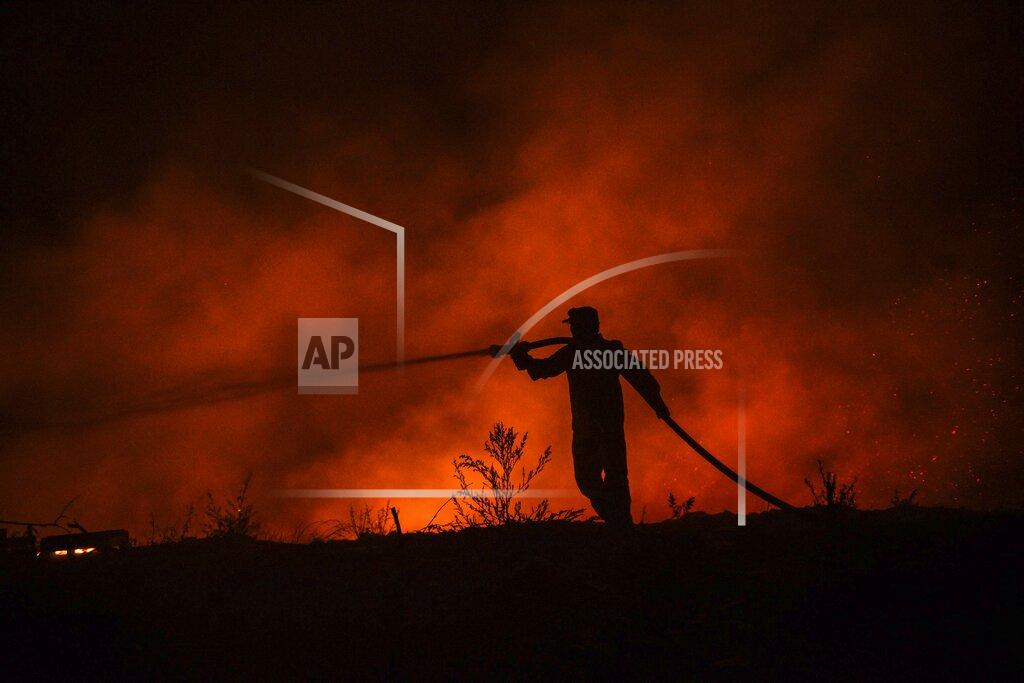 Uncredited A firefighter battles with fire in Kirli village near the town of Manavgat, in Antalya province, Turkey early Friday July 30, 2021. The fire that continued all night could not be brought under control and people living in the village started to evacuate. Wildfires are common in Turkey's Mediterranean and Aegean regions during the arid summer months, although some previous forest fires have been blamed on arson.(AP Photo)