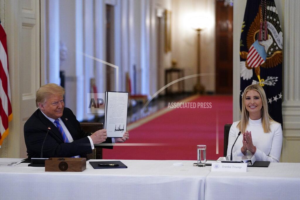 FILE - In this June 26, 2020, file photo, Ivanka Trump, right, applauds as President Donald Trump holds an executive order that he signed during a meeting with the American Workforce Policy Advisory Board, in the East Room of the White House in Washington. A new White House-backed ad campaign aims to encourage people who are unemployed or unhappy in their jobs or careers to “find something new.” (AP Photo/Evan Vucci, File)