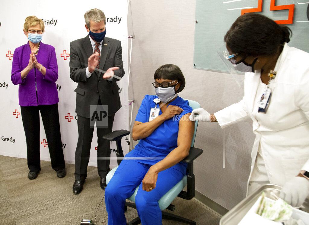 Steve Schaefer Georgia Gov. Brian Kemp, second from left, and Dr. Kathleen Toomey, left, applaud after Grady ICU nurse Norma Poindexter received her Pfizer-BioNTech COVID-19 vaccine at Grady Hospital, Thursday, Dec. 17, 2020, in Atlanta. (Steve Schaefer/Atlanta Journal-Constitution via AP)