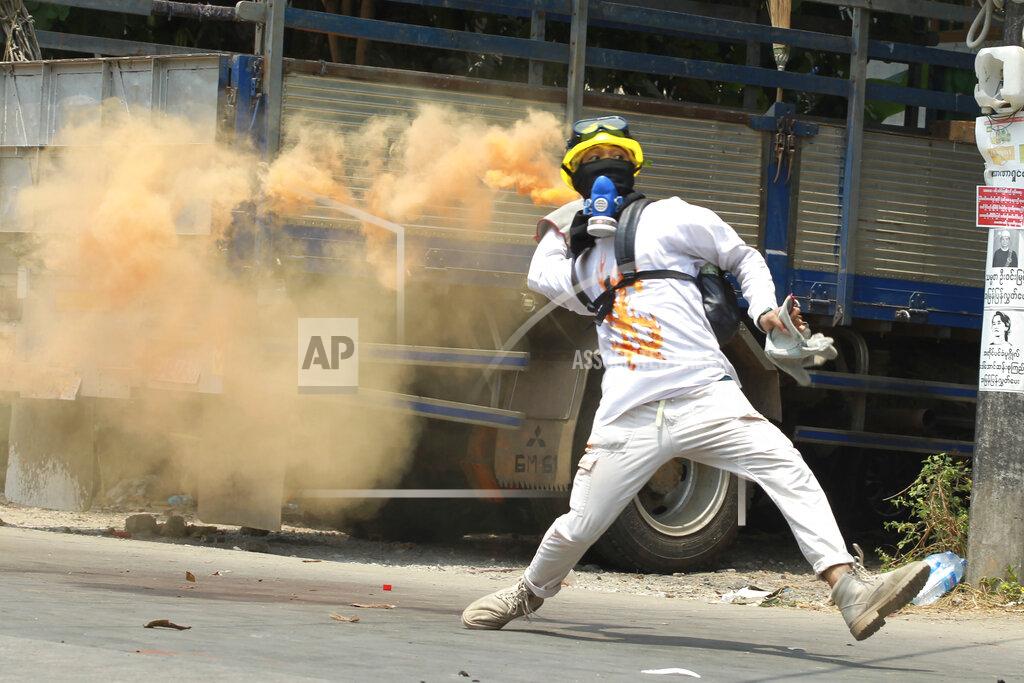 Uncredited FILE - In this March 27, 2021, file photo, an anti-coup protester throws a smoke bomb against police during a crackdown in Thaketa township in Yangon, Myanmar. Former United Nations Secretary General Ban ki-Moon is urging the world body and Southeast Asian countries to take swift and "strong action" to stop the deadly crackdown that has followed a military coup in Myanmar. (AP Photo/File)