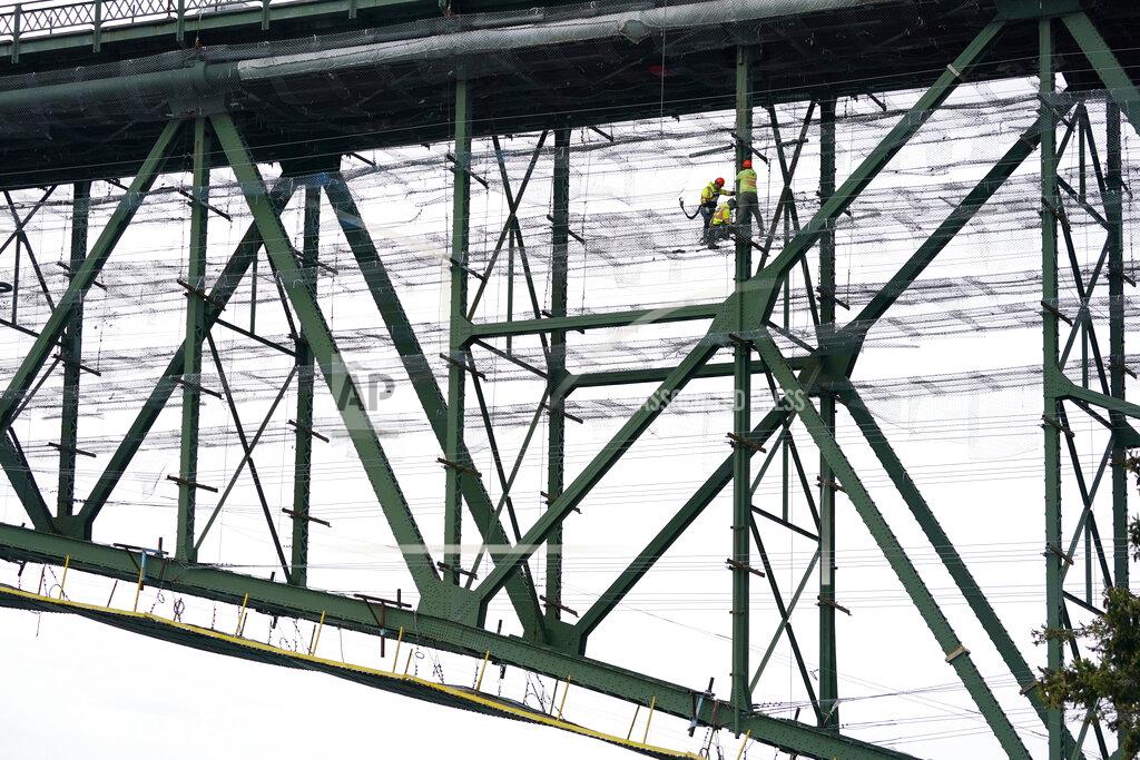Elaine Thompson Workers stand on wire mesh below the decking of the Deception Pass Bridge, nearly 1,000-feet long and about 180-feet above the waters below, as work to replace corroded steel and paint the structure continues Thursday, April 29, 2021, in Deception Pass, Wash. Raising state taxes to improve roads and bridges is one of the few things many Republican and Democratic lawmakers have agreed on in recent years. Those efforts have slowed to a crawl this year, even as lawmakers acknowledge a widening gap between needed work and the money to pay for it. (AP Photo/Elaine Thompson)