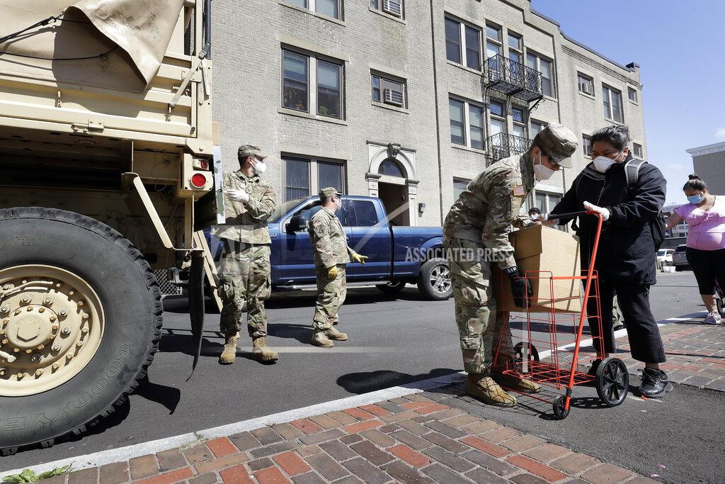 Massachusetts National Guard soldiers from the 181st Engineer Company, left, wear masks out of concern for the coronavirus as they distribute boxes of food, Tuesday, May 5, 2020, to people also wearing masks in Chelsea, Mass. (AP Photo/Steven Senne)