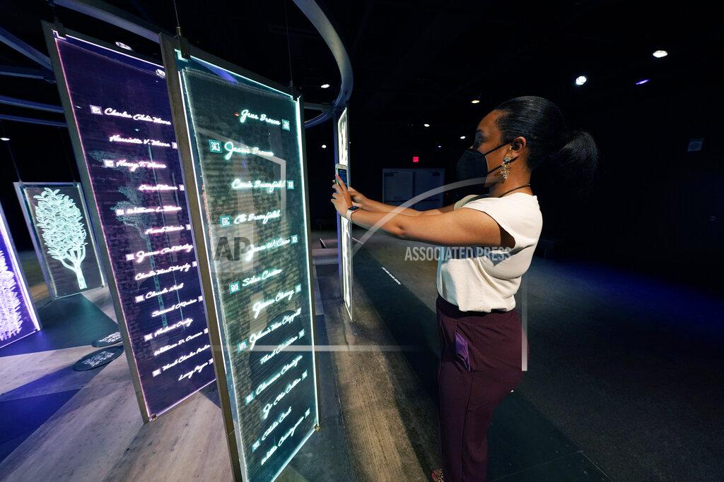 Rogelio V. Solis Laurin Paris, director of public relations with the Two Mississippi Museums in Jackson, uses her cell phone to scan the QR code from the PBS Frontline's traveling augmented-reality exhibit, "Un(re)solved" in the museum's special exhibit room, Friday, Aug. 27, 2021. The exhibit opened Saturday, Aug. 28, to align with the commemoration of the death of Emmett Till, a Chicago teenager who was lynched in Mississippi in 1955. The multi-media platform allows the visitor to download both dialogue and text on each person listed as it examines the federal government's efforts to investigate more than 150 civil rights era cold cases on the Emmett Till Unsolved Civil Rights Crime Act. (AP Photo/Rogelio V. Solis)