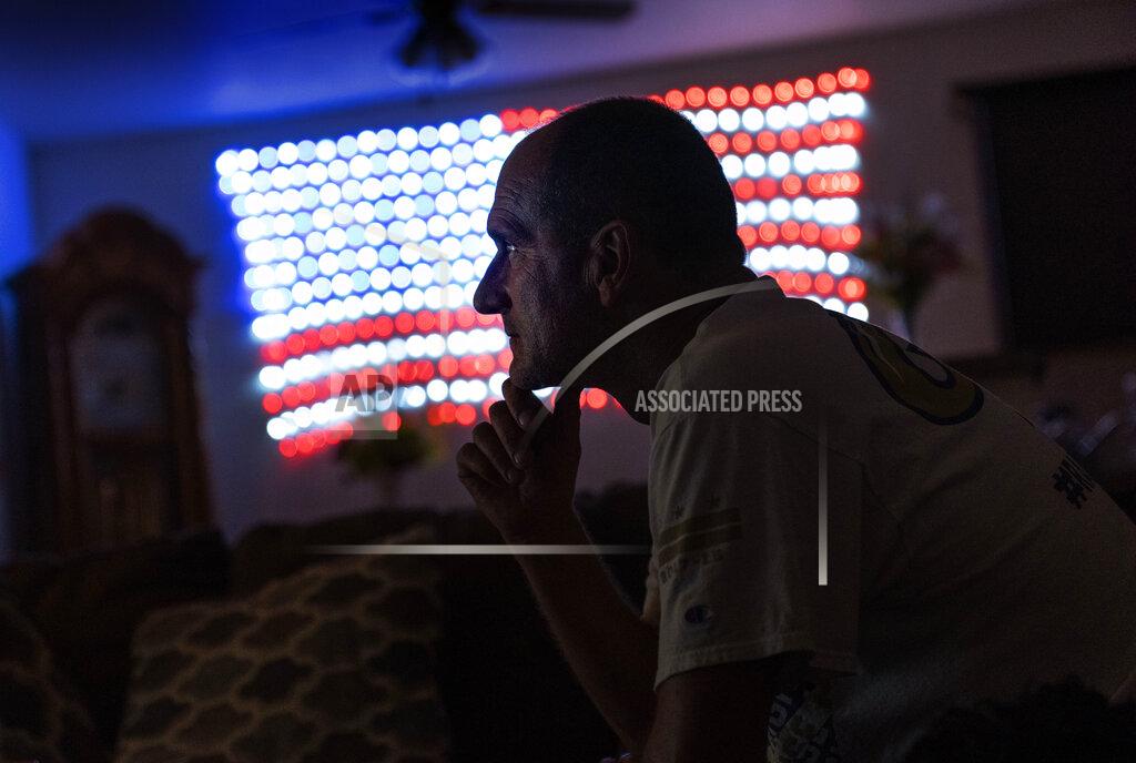 David Goldman Scott Rice sits in his living room watching a Fox News Channel interview with President Donald Trump in Appleton, Wis., Aug. 20, 2020. Nothing can shake Rice's faith that Trump will save the U.S. economy, not seeing businesses close or friends furloughed, not even his own hellish bout with the coronavirus. But in Appleton, a city of 75,000 people along the Fox River, the health of economy isn't judged on jobs numbers, personal bank accounts or union contracts. Instead, it's viewed through partisan lenses, filtered through the facts voters want to see and hear, and those they don't. (AP Photo/David Goldman)