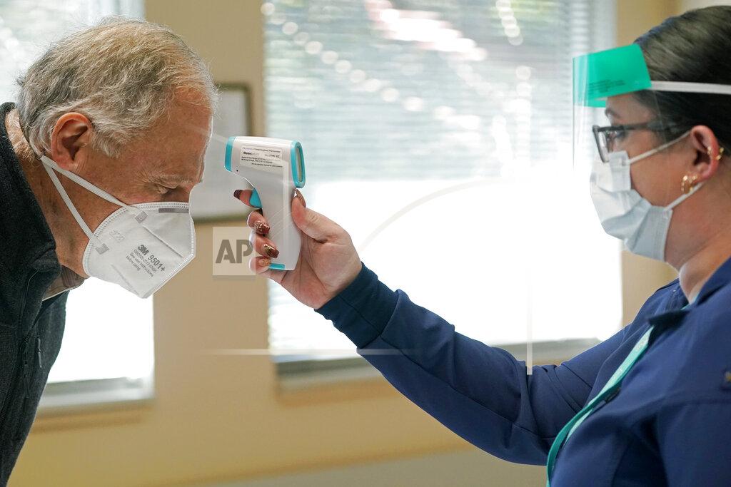 Ted S. Warren Washington Gov. Jay Inslee, left, has his temperature taken by Elizabeth Smalley, right, a medical assistant at a Sea Mar Community Health Center, before he received the first shot of the Moderna COVID-19 vaccine, Friday, Jan. 22, 2021, in Olympia, Wash. Inslee's wife Trudi also received the first dose of the vaccine. (AP Photo/Ted S. Warren)