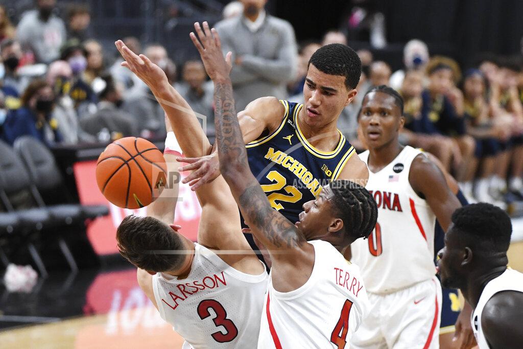 Sam Morris Michigan forward Caleb Houstan (22) passes between Arizona guard Pelle Larsson (3) and guard Dalen Terry (4) during an NCAA college basketball game Sunday, Nov. 21, 2021, in Las Vegas. (AP Photo/Sam Morris)