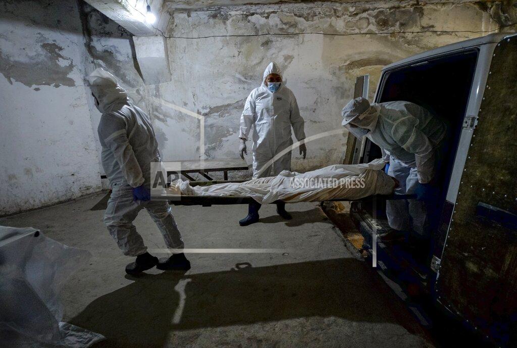 Vladimir Voronin Pathologists in protective suits transport the body of a person who died of the coronavirus at a hospital's morgue in Bishkek, Kyrgyzstan, Wednesday, July 22, 2020. Coronavirus cases surged in Kyrgyzstan after authorities lifted a tight lockdown in May, overwhelming the health care system. But now thousands of volunteers are helping medical workers in busy hospitals, using cars into makeshift ambulances and finding protective gear, drugs, supplies and equipment. (AP Photo/Vladimir Voronin)