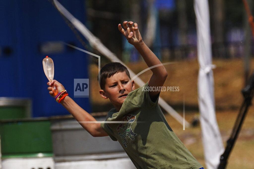 Marco Ugarte A child winds-up as he takes aim during a water balloon fight at a camp in the Iztapalapa borough of Mexico City, Tuesday, May 24, 2022. Mexico City will close the camp that has hosted hundreds of Ukrainian refugees for the past month. Now that a U.S. program vetting refugees and then allowing them to fly to the U.S. is operational, authorities say the camp is no longer needed. (AP Photo/Marco Ugarte)