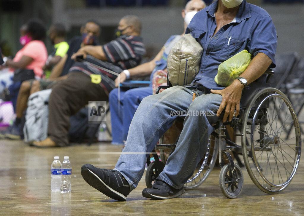 Rick Hickman Southwest Louisiana residents wait for buses at Burton Coliseum in Lake Charles, La. to be evacuated to a shelter in Alexandria, La., Tuesday, Aug. 25, 2020. (Rick Hickman/American Press via AP)