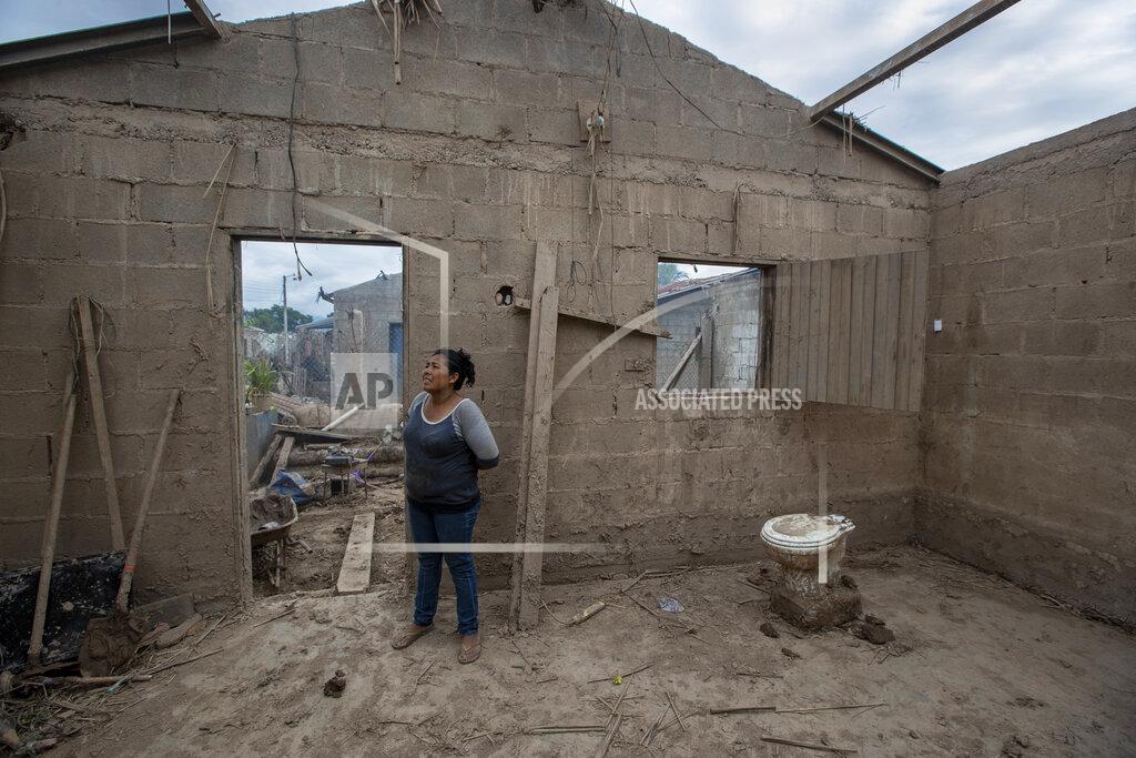 Moises Castillo Maria Elena Vasquez stands inside what's left of her home after last year's hurricanes Eta and Iota in La Lima, on the outskirts of San Pedro Sula, Honduras, where she returns every afternoon to remove the mud in hopes of returning to live here, Wednesday, Jan. 13, 2021. Twenty-two years before the 2020 storms, Hurricane Mitch destroyed Vasquez's other home, which was replaced with this one, built by a Catholic charity from Canada. (AP Photo/Moises Castillo)
