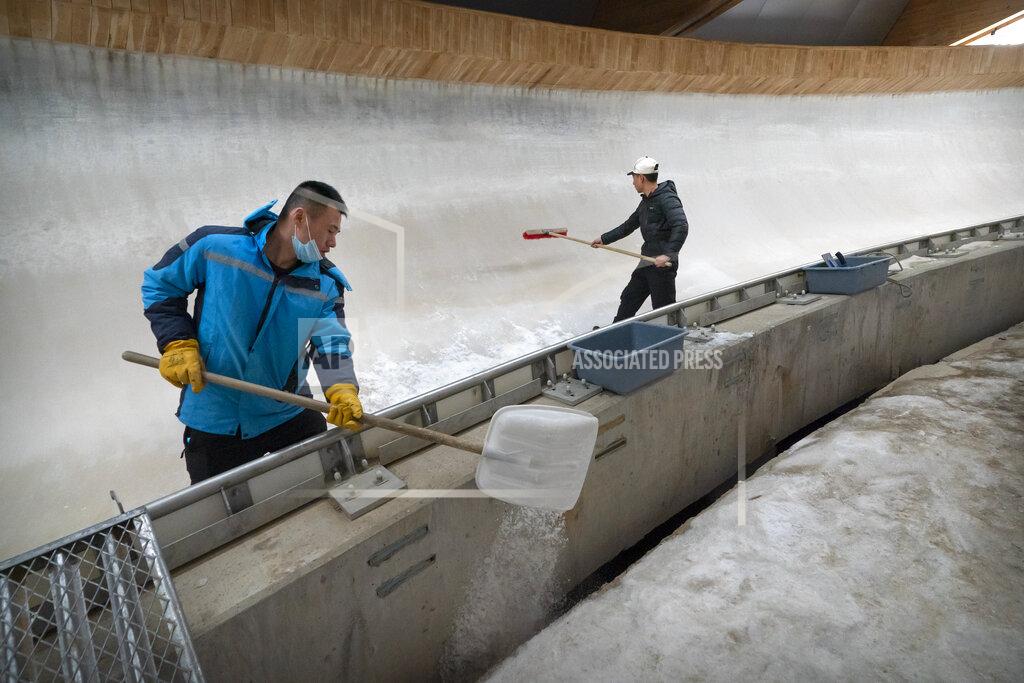 Mark Schiefelbein Workers clear the ice at the National Sledding Center in Yanqing on the outskirts of Beijing, Friday, Feb. 5, 2021. Beijing Olympic organizers showed off the downhill skiing venue and the world's longest bobsled and luge track Friday, one year ahead of the scheduled opening of the 2022 Olympic Winter Games. (AP Photo/Mark Schiefelbein)