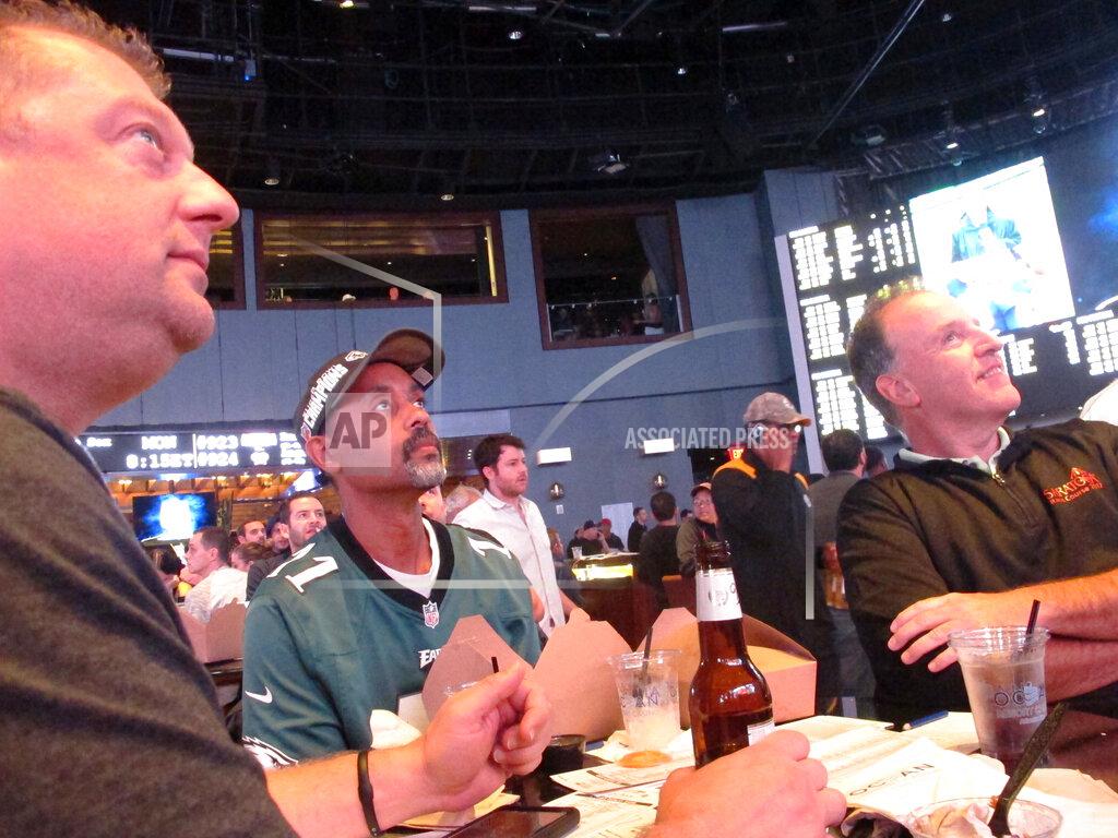 Wayne Parry In this Sept. 9, 2019 photo, football fans watch the action on-wall-mounted video screens in the sports betting lounge at the Ocean Casino Resort in Atlantic City, N.J. The coronavirus outbreak has added new wrinkles for bettors this year, but even so, the nation's sportsbooks expect a record year of bets on football in 2020 from an antsy public that has been cooped up for months amid the pandemic. (AP Photo/Wayne Parry)