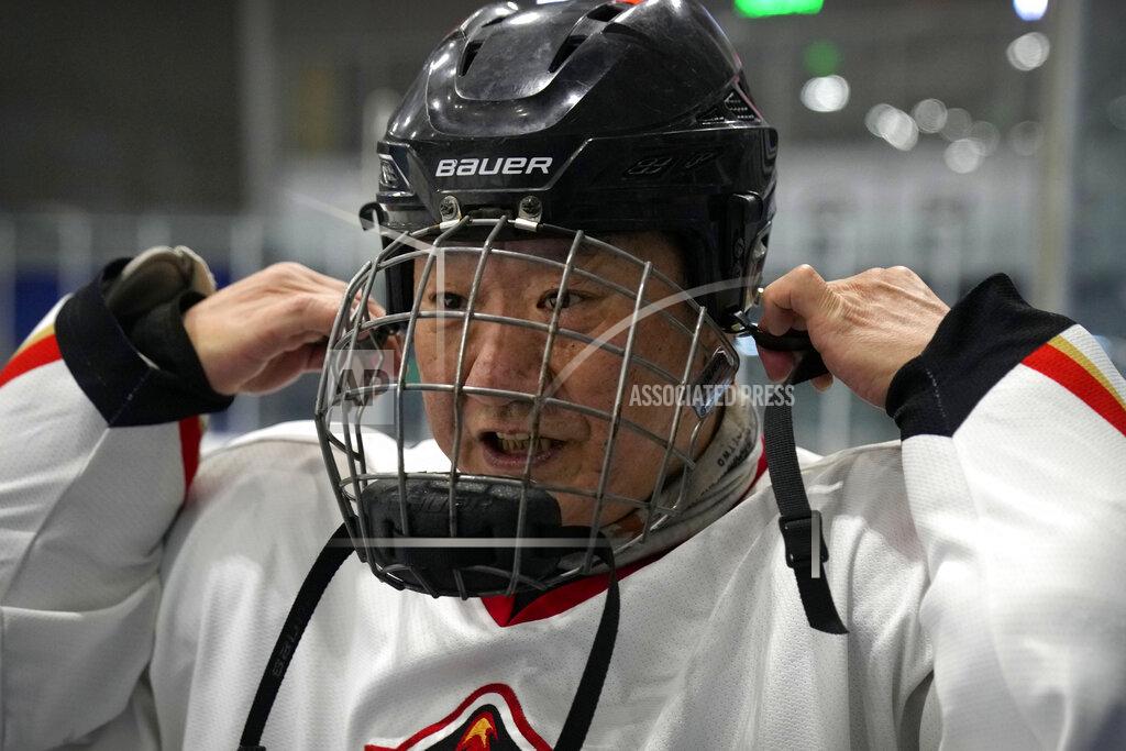 Mark Schiefelbein A member of the "1979" hockey club puts on his helmet during a break between periods in a hockey match at a rink in Beijing, Wednesday, Jan. 12, 2022. Spurred by enthusiasm after China was awarded the 2022 Winter Olympics, the members of a 1970s-era youth hockey team, now around 60 years old, have reunited decades later to once again take to the ice. (AP Photo/Mark Schiefelbein)