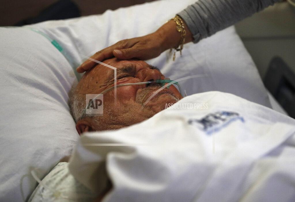 Hussein Malla FILE - In this July 16, 2020 file photo, a patient is comforted by a relative, at Family Medical Center, in Majdalaiya village, north Lebanon. The confirmed death toll from the coronavirus has gone over 50,000 in the Middle East as the pandemic continues. That's according to a count Thursday, Sept. 3, 2020, from The Associated Press, based on official numbers offered by health authorities across the region. (AP Photo/Hussein Malla, File)