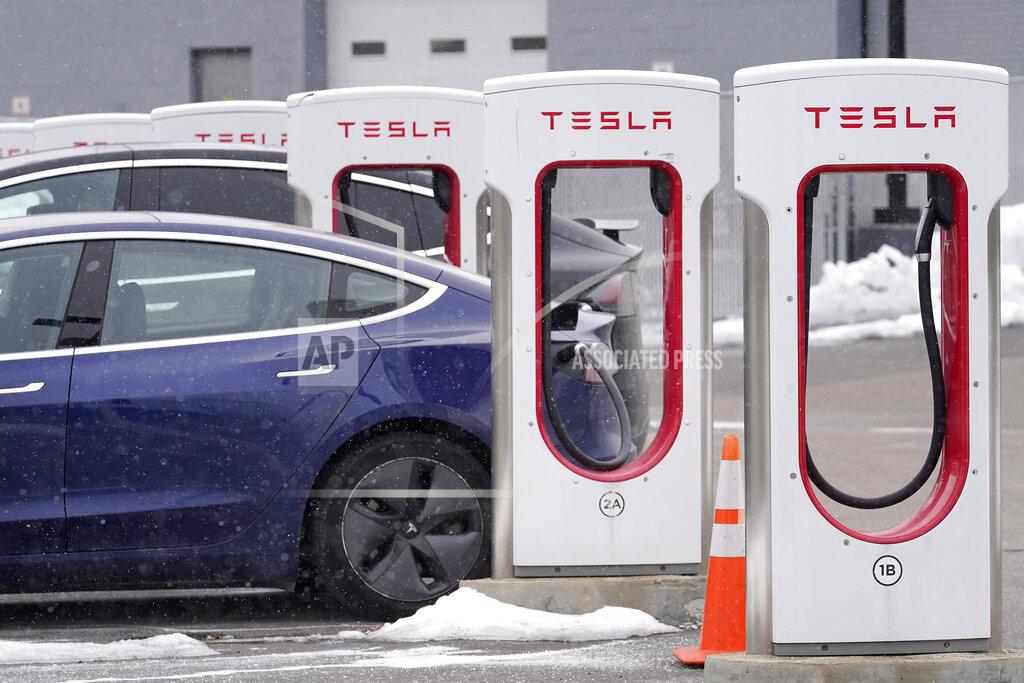 Steven Senne A Tesla electric vehicle, left, sits in a charging station at a dealership, Thursday, Feb. 18, 2021, in Dedham, Mass. After a year of ghostly airports, empty sports stadiums and constant Zoom meetings, growing evidence suggests that the economy is strengthening. Hiring picked up in February 2021. Business restrictions have eased as the pace of viral infections has ebbed. Yet the economy remains far from normal. (AP Photo/Steven Senne)
