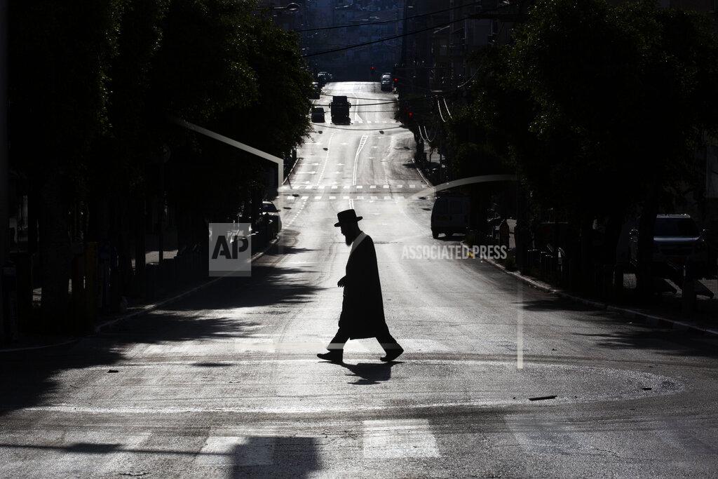 Oded Balilty An ultra-Orthodox Jew crosses a mainly deserted street because of the government's measures to help stop the spread of the coronavirus, in Bnei Brak, Israel, Wednesday, April 8, 2020. Israeli Prime Minister Benjamin Netanyahu announced Monday a complete lockdown over the upcoming Passover feast to control the country's coronavirus outbreak, but offered citizens some hope by saying he expects to lift widespread restrictions after the week-long Jewish holiday. (AP Photo/Oded Balilty)