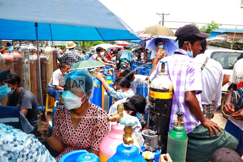 Uncredited People wait in line next to oxygen tanks to be refilled outside the Naing oxygen factory at the South Dagon industrial zone in Yangon, Myanmar, Wednesday, July 28, 2021. Myanmar is currently reeling from soaring numbers of COVID-19 cases and deaths that are badly straining the country’s medical infrastructure. (AP Photo)