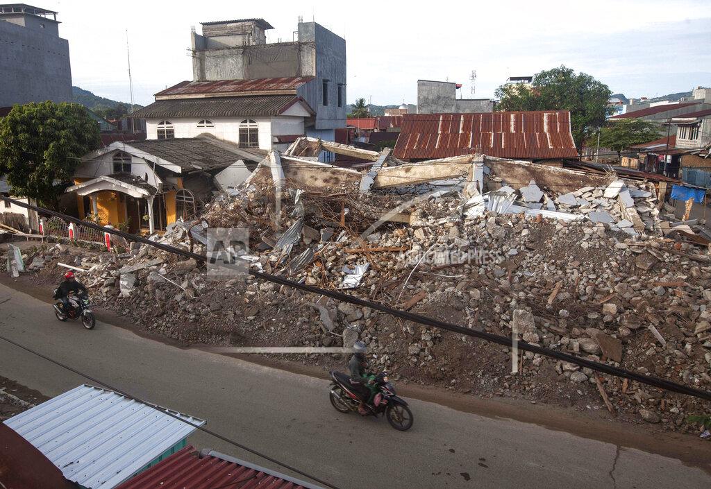 Yusuf Wahil Motorists ride past buildings collapsed in Friday's earthquake in Mamuju, West Sulawesi, Indonesia, Monday, Jan. 18, 2021. Aid was reaching the thousands of people left homeless and struggling after an earthquake that killed a number of people in the province where rescuers intensified their work Monday to find those buried in the rubble. (AP Photo/Yusuf Wahil)