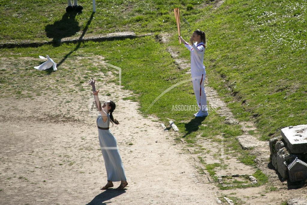 Yorgos Karahalis Greek actress Xanthi Georgiou, left, playing the role of the High Priestess, releases a dove as Greek shooting Olympic champion Anna Korakaki, the first torchbearer, holds the torch of the 2020 Tokyo Olympic Games during the flame lighting ceremony at the closed Ancient Olympia site, birthplace of the ancient Olympics in southern Greece, Thursday, March 12, 2020, 2020. Greek Olympic officials are holding a pared-down flame-lighting ceremony for the Tokyo Games due to concerns over the spread of the coronavirus. Both Wednesday's dress rehearsal and Thursday's lighting ceremony are closed to the public, while organizers have slashed the number of officials from the International Olympic Committee and the Tokyo Organizing Committee, as well as journalists at the flame-lighting. (AP Photo/Yorgos Karahalis)